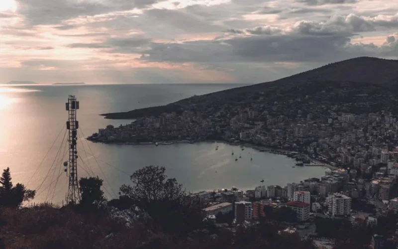 A serene view of Saranda, Albania cityscape and coastline at dusk with a distant television tower.