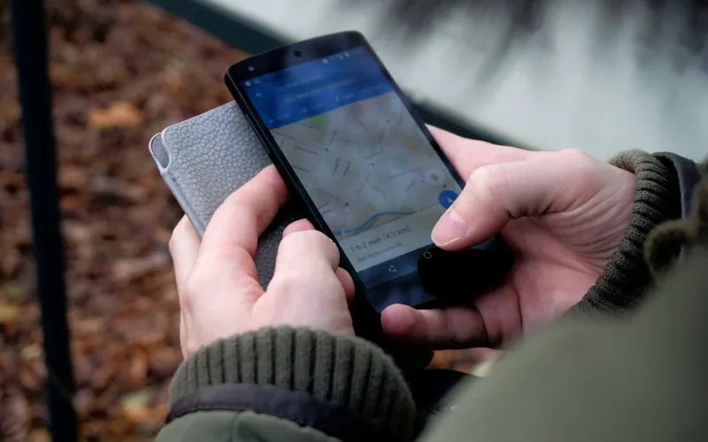 Close-up of hands using a map app on a smartphone outdoors, showcasing GPS navigation.