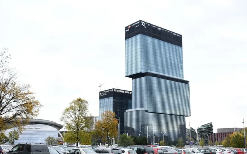 Modern architecture of an office building in Katowice, Poland, with cars and trees in the foreground.