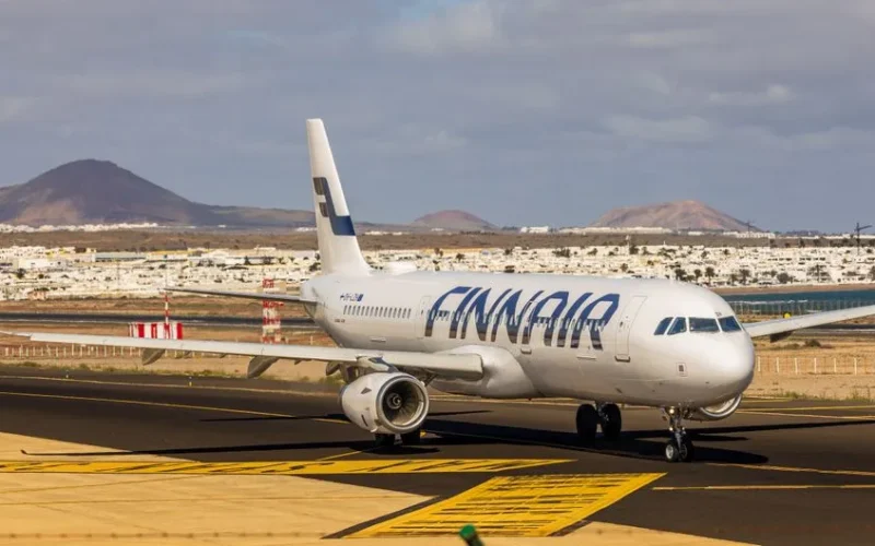 Finnair aircraft on runway with Lanzarote's volcanic landscape in background.