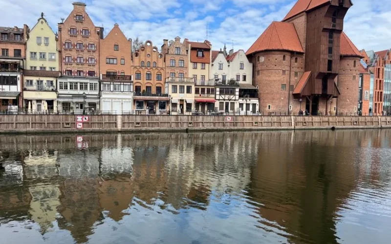 Beautiful reflection of historic Gdańsk architecture along the Motława River on a clear day.