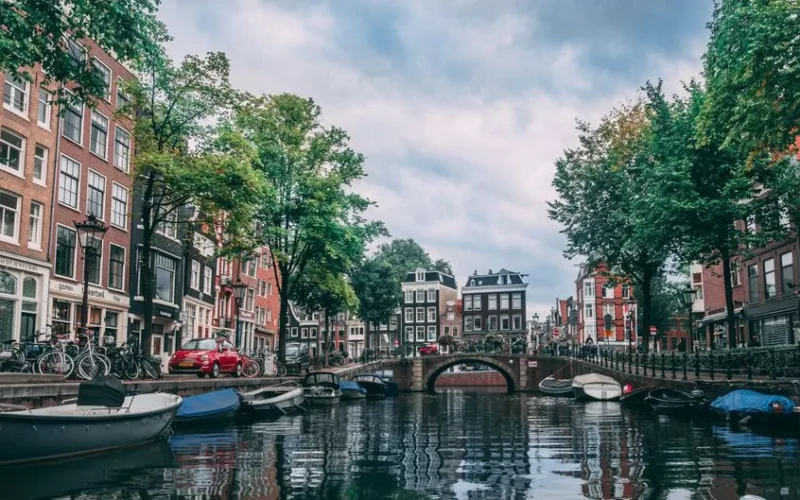 Charming view of an Amsterdam canal lined with bicycles, boats, and historic buildings.