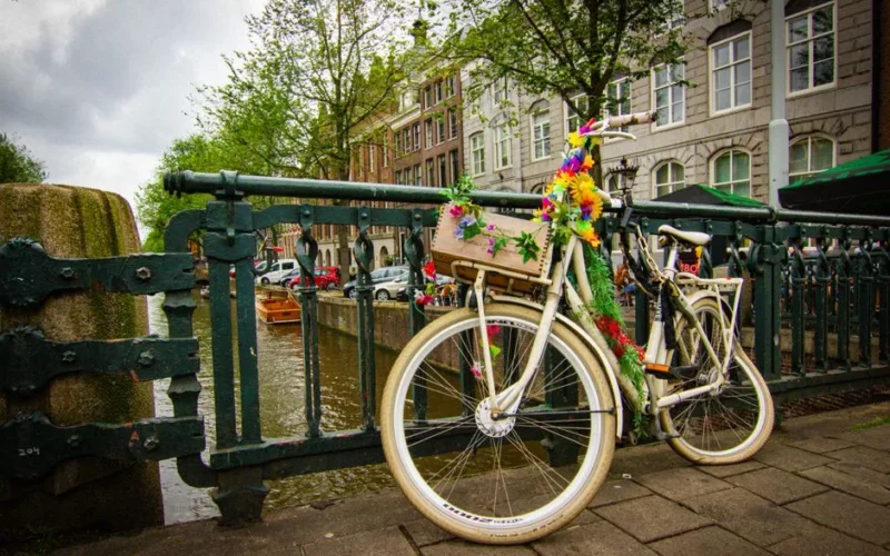 A flower-adorned bicycle rests against a bridge along Amsterdam's picturesque canals.