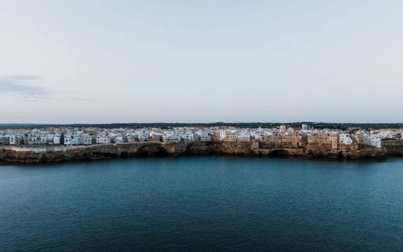 A stunning aerial view of Polignano a Mare, Italy, showcasing its cliffside architecture by the sea.