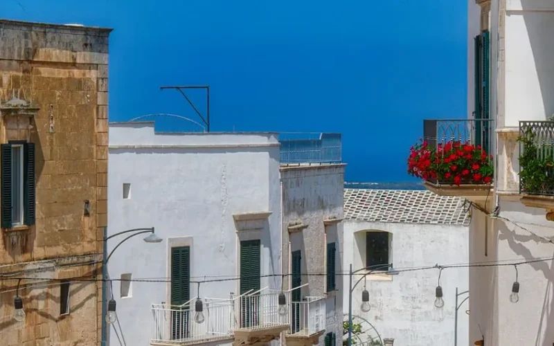 Explore the picturesque whitewashed buildings and vibrant balconies of Ostuni, Italy.
