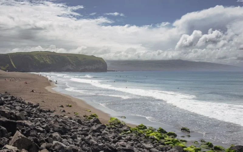 Tranquil beach view with cliffs and clouds on São Miguel Island, Azores.