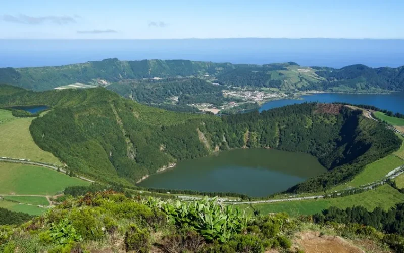 A stunning aerial view of a lush green landscape featuring a crater lake surrounded by hills and valleys.