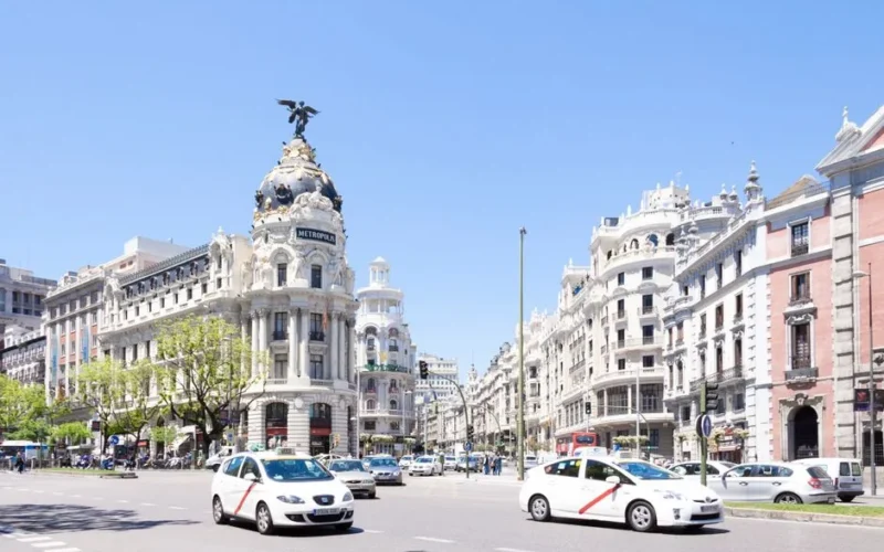 Stunning view of Madrid's landmark Metropolis Building on a sunny day with traffic flowing by.