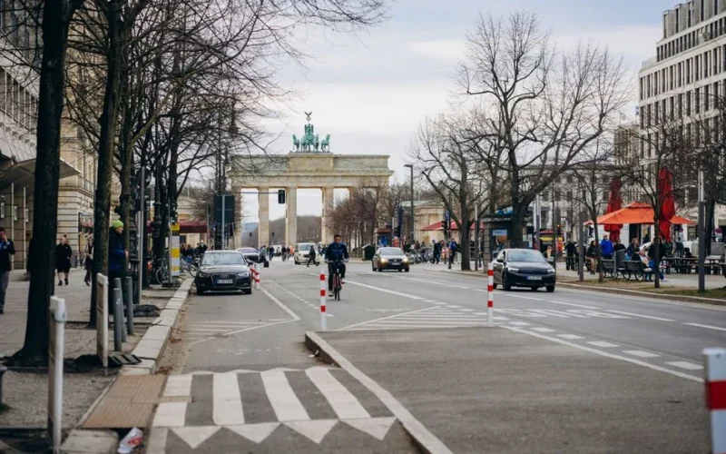 Street scene with Brandenburg Gate in Berlin, showcasing urban life and historic architecture.