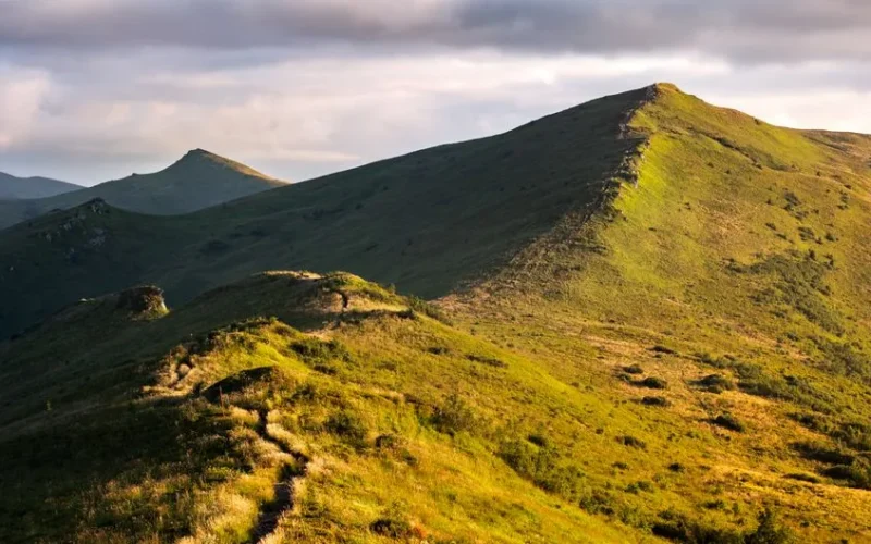 Bieszczady mountain range with green valleys and trails in early morning light, perfect for hiking adventures.