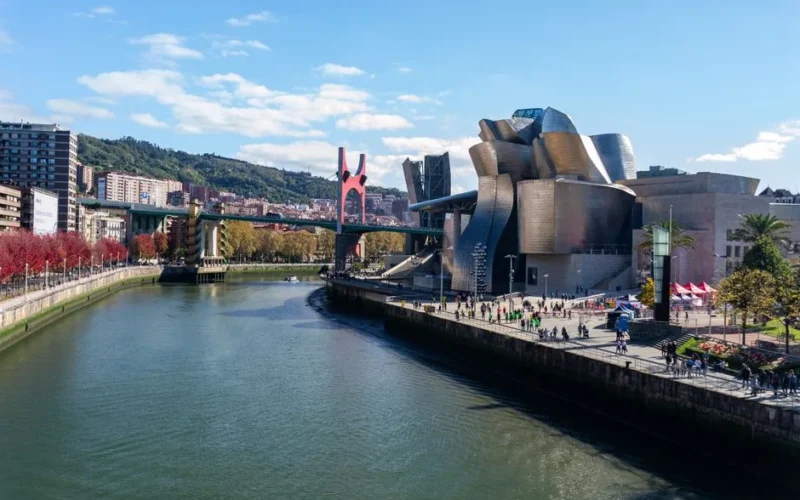 A stunning view of Guggenheim Museum Bilbao alongside a scenic river and urban landscape.