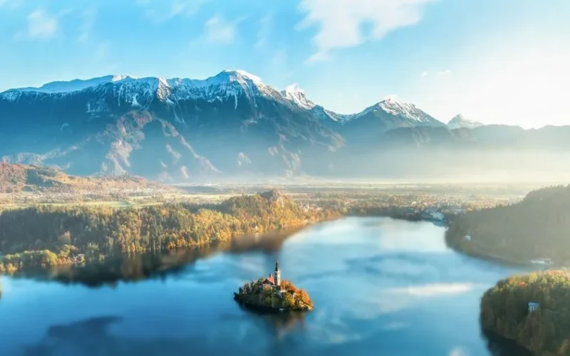 Majestic Lake Bled with church on island, surrounded by Julian Alps under sunset light.
