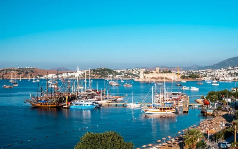 A stunning view of Bodrum's marina with sailboats and the historic Bodrum Castle on a sunny day.