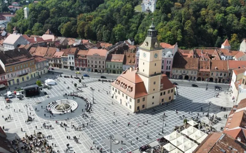 Aerial shot of the vibrant town square in Brașov, showcasing historic architecture and bustling activity.