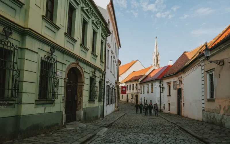 Charming cobblestone street in Old Town Bratislava with historic architecture and pedestrians.