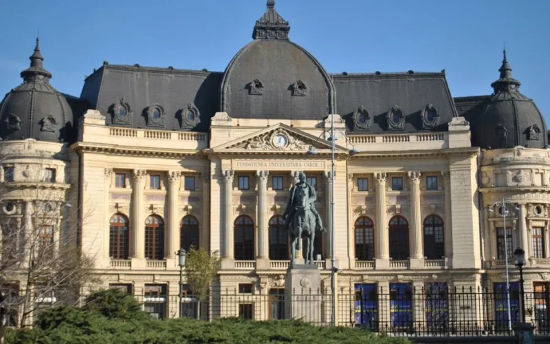 Elegant historic university building featuring an equestrian statue in a sunny outdoor setting.