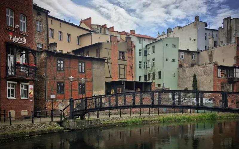 Picturesque view of historic buildings and footbridge in Bydgoszcz, Poland, reflecting urban charm.
