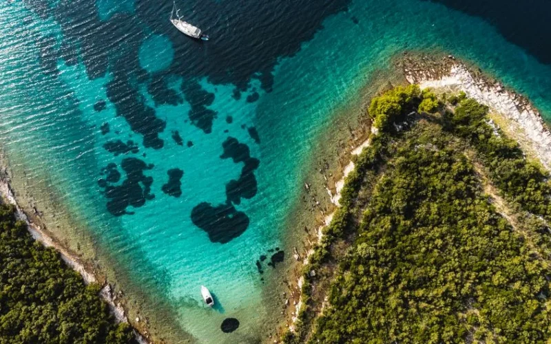 Stunning aerial shot of Croatia's coastline with clear turquoise waters and lush greenery.