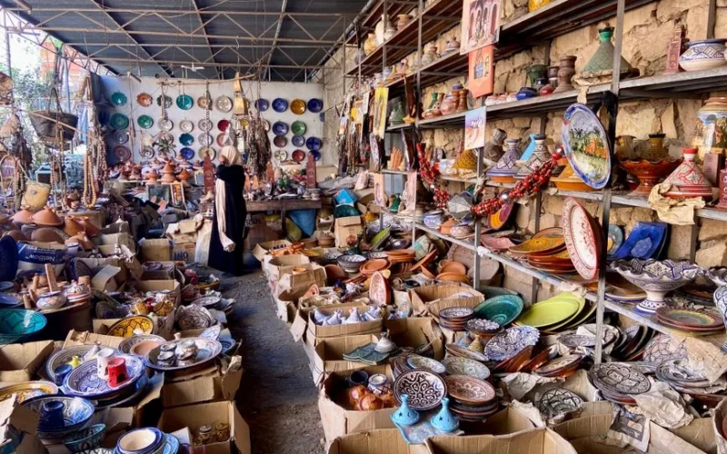 Traditional Moroccan pottery and ceramics displayed in bustling market stall, offering a vibrant cultural experience.