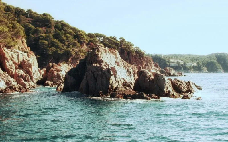 Dramatic rocky cliffs meeting the azure sea in Costa Brava, Spain. Ideal summer escape.