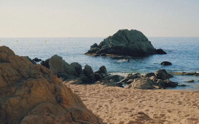 Picturesque beach scene in Costa Brava featuring clear water and prominent rock formations.