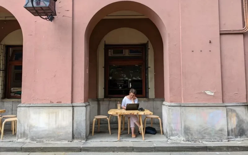 Woman working on a laptop outside a cafe in Warsaw, Poland. Relaxing, urban vibe.