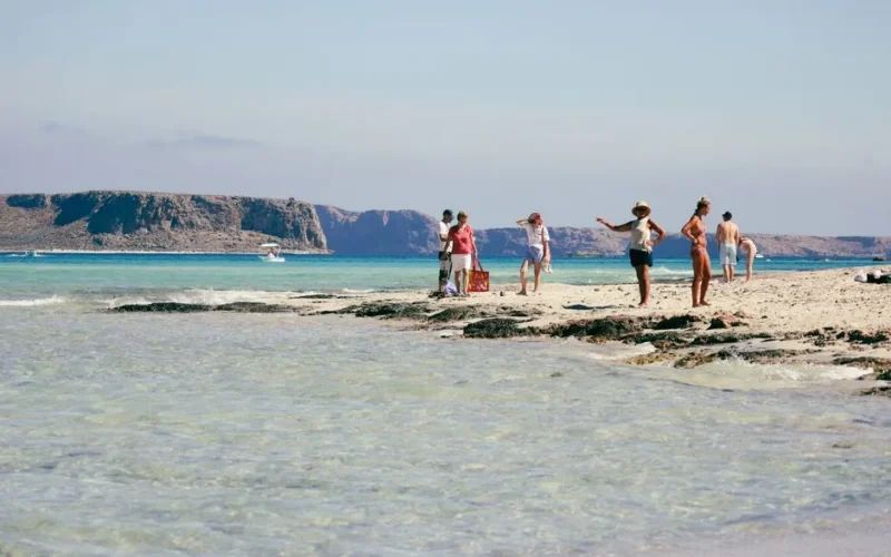 A sunny day at Balos Lagoon in Greece with people enjoying the beach and clear blue waters.