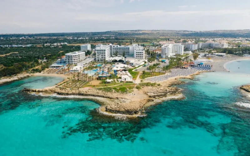 Stunning aerial shot of a Cyprus seaside resort showcasing crystal clear waters and luxury hotels.