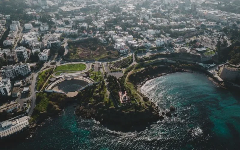 A stunning aerial photo capturing the coastal cityscape with an ancient amphitheater and blue sea.