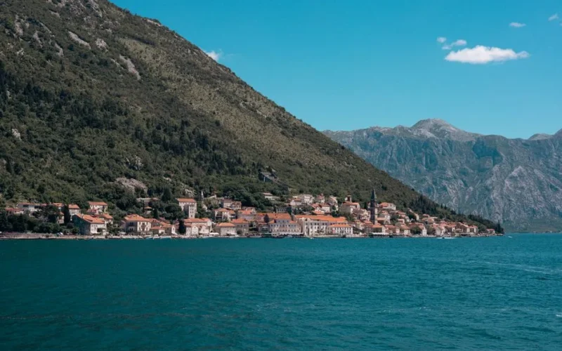 Beautiful seaside town along the Bay of Kotor with mountains and clear blue water.