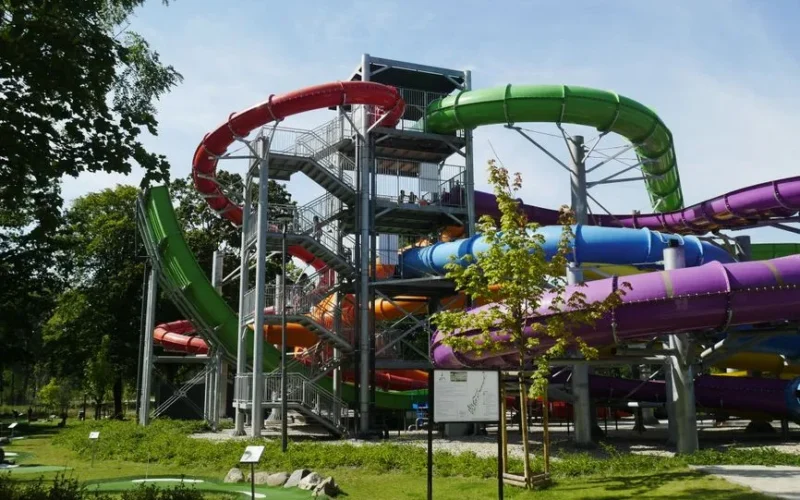 Colorful water slides spiral at a sunny outdoor park in Zielona Góra, Poland.