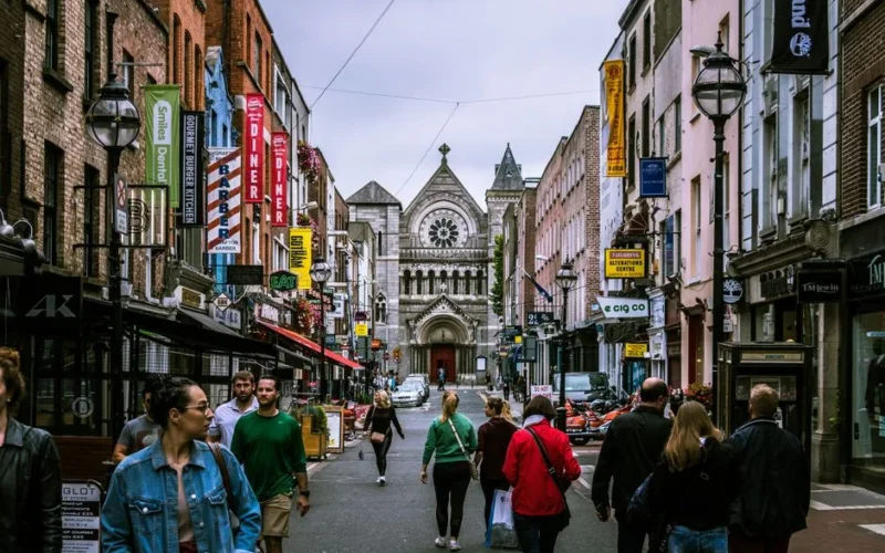 A bustling street scene in Dublin, showcasing diverse people and historic architecture.