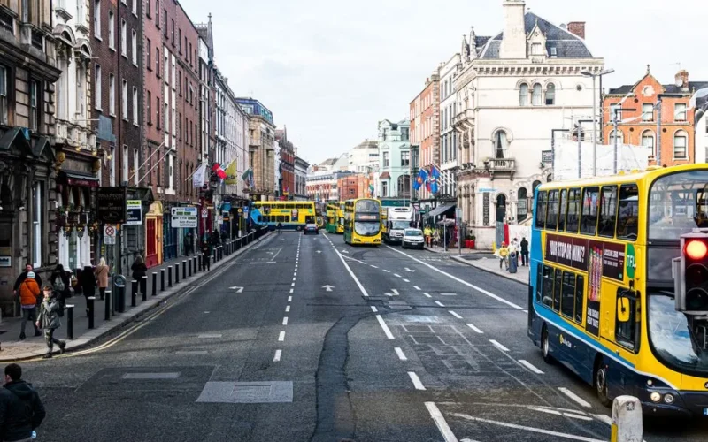 Vibrant city street scene in Dublin with buses and pedestrians on a busy day.