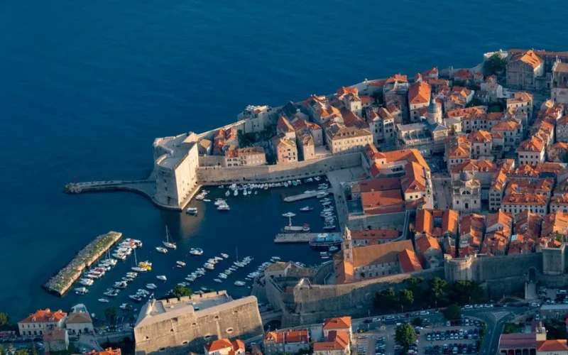 Stunning aerial shot of Dubrovnik's old town and harbor, showcasing its iconic medieval walls and Adriatic Sea views.