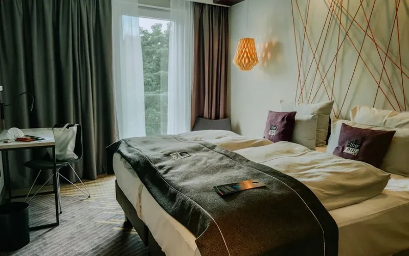 A modern and cozy hotel room featuring a double bed, stylish lighting, and a workspace.