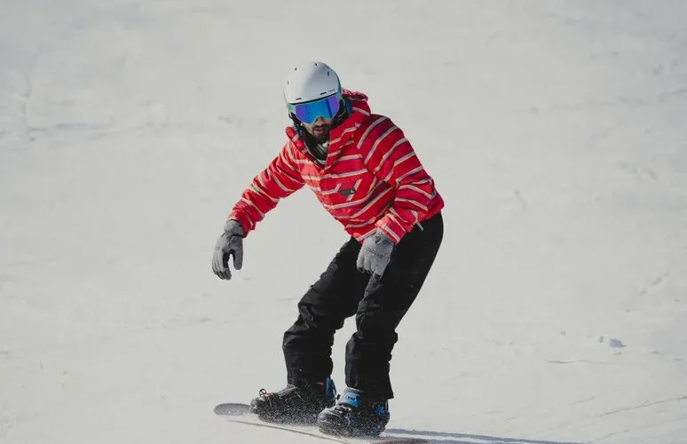 A snowboarder wearing a red jacket glides down a snowy slope, capturing winter adventure.