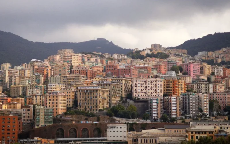 Scenic view of colorful residential buildings on Genoa's hillside under cloudy skies.