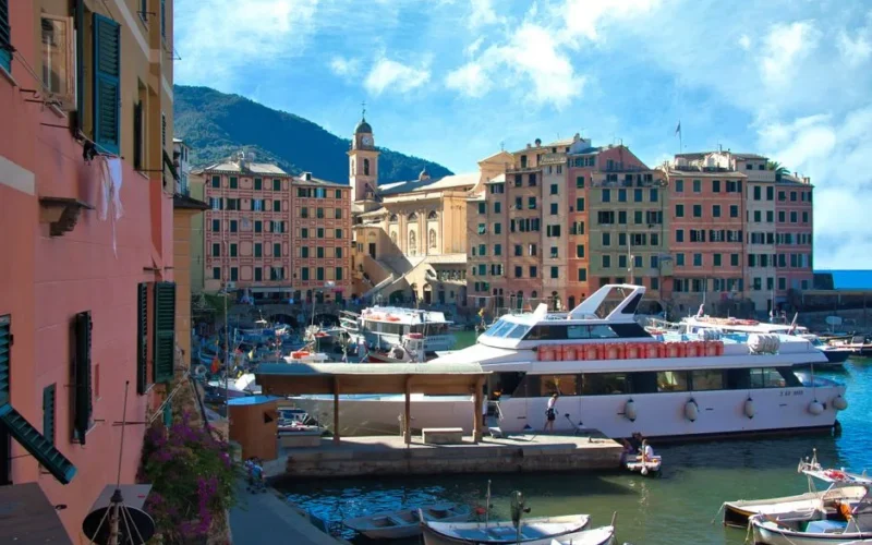 Explore Camogli's vibrant harbor with colorful buildings and boats under a bright blue sky.