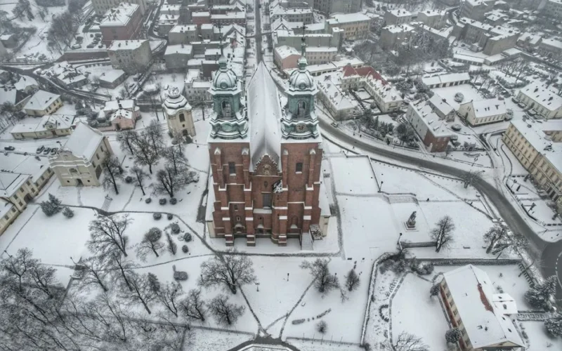 Drone shot of Royal Gniezno Cathedral blanketed in snow, Poland's historic landmark.
