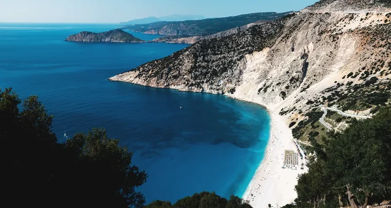 Discover the breathtaking aerial view of Myrtos Beach in Greece with turquoise waters and surrounding cliffs.