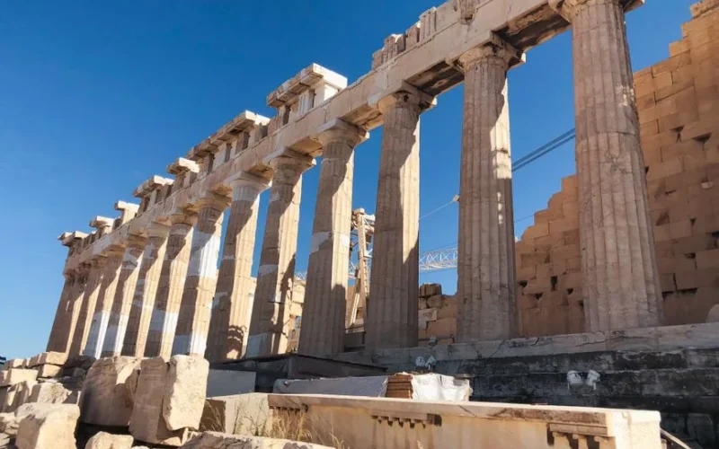 The iconic Parthenon columns in Athens, showcasing ancient Greek architecture under a bright blue sky.