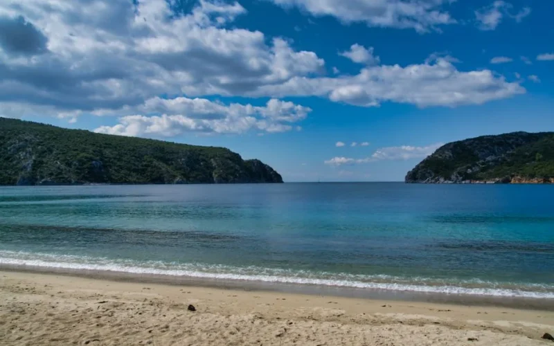 Peaceful Greek beach scene with turquoise waters and a clear blue sky, ideal for summer vacations.