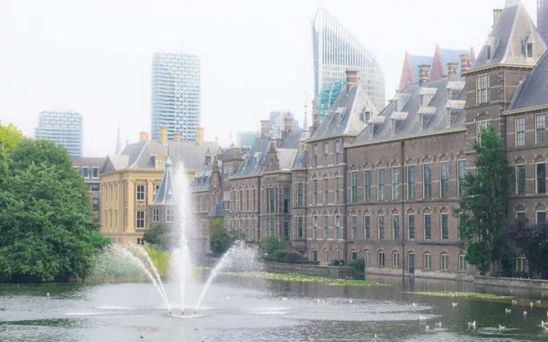 The Binnenhof in The Hague with a fountain and urban skyline backdrop.