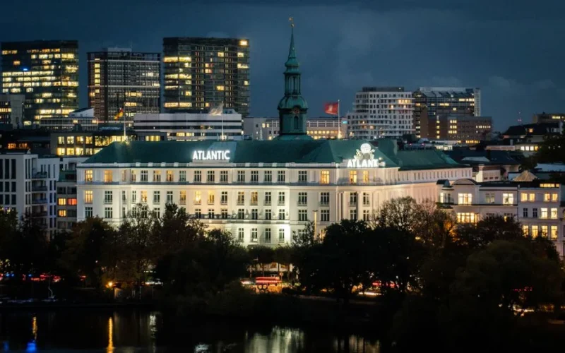 Stunning view of the illuminated Hotel Atlantic in Hamburg reflecting city lights at night.