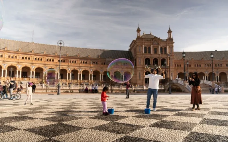 A joyful scene of people playing with bubbles at Plaza de España in Seville, Spain.