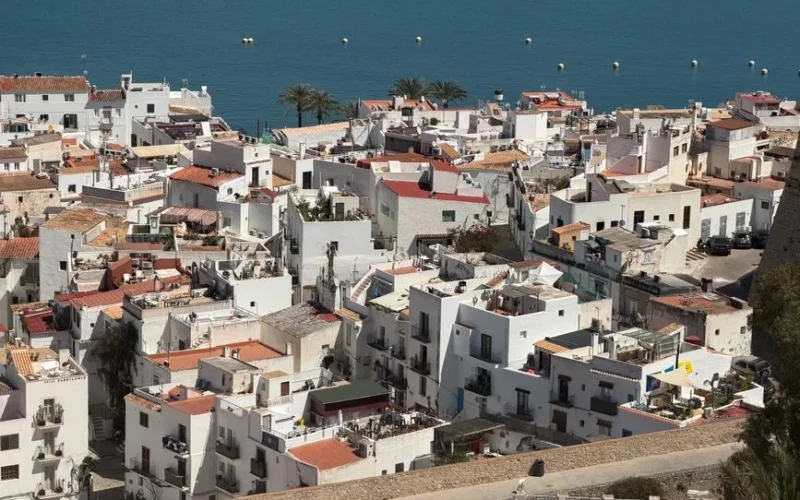 Aerial perspective of the picturesque whitewashed buildings in Eivissa, Ibiza with a stunning sea backdrop.