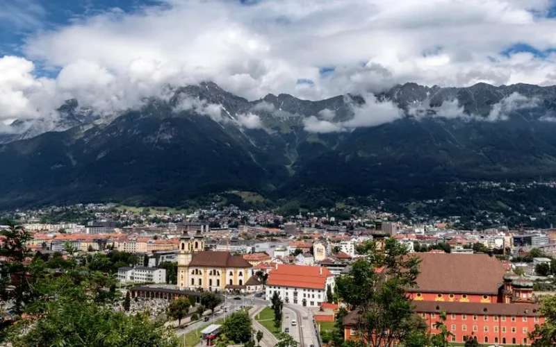 A breathtaking aerial view of Innsbruck, Austria, framed by majestic mountains and vibrant urban life.