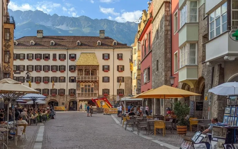 Scenic view of Innsbruck's historic Goldenes Dachl surrounded by colorful buildings and lively streets.