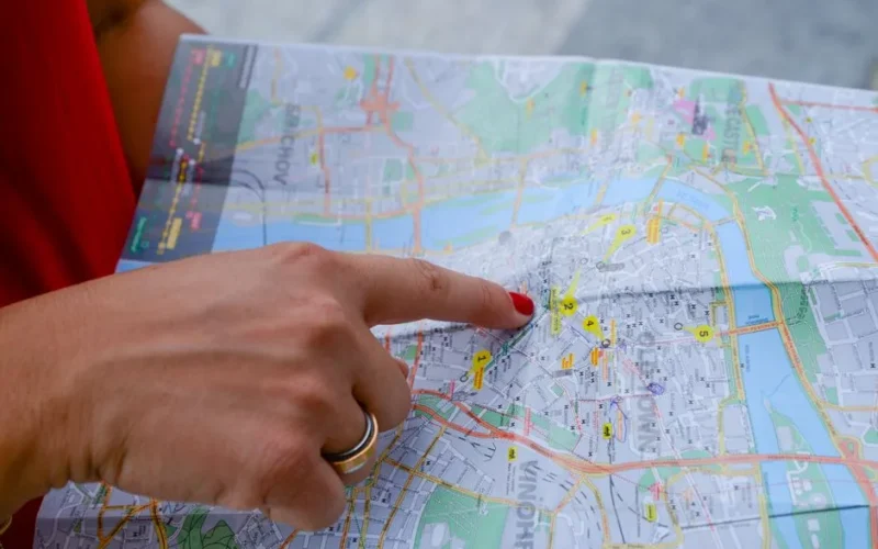 A person with a red shirt points at a city map indicating travel guidance. Perfect for tourism concepts.