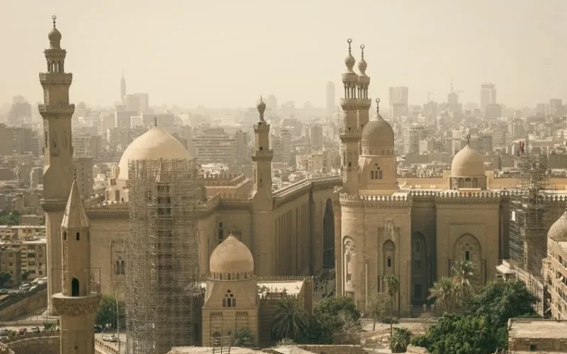 Panoramic view of Cairo featuring historic mosque architecture against the city skyline.